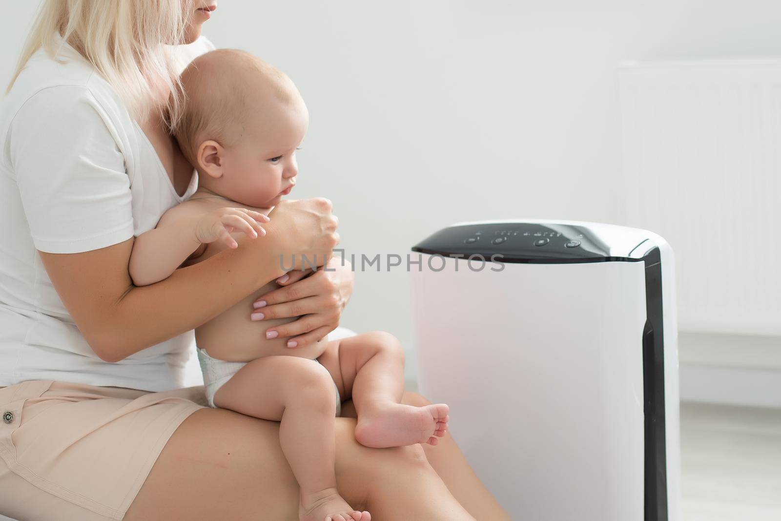 mother and baby near air purifier at home. by Andelov13