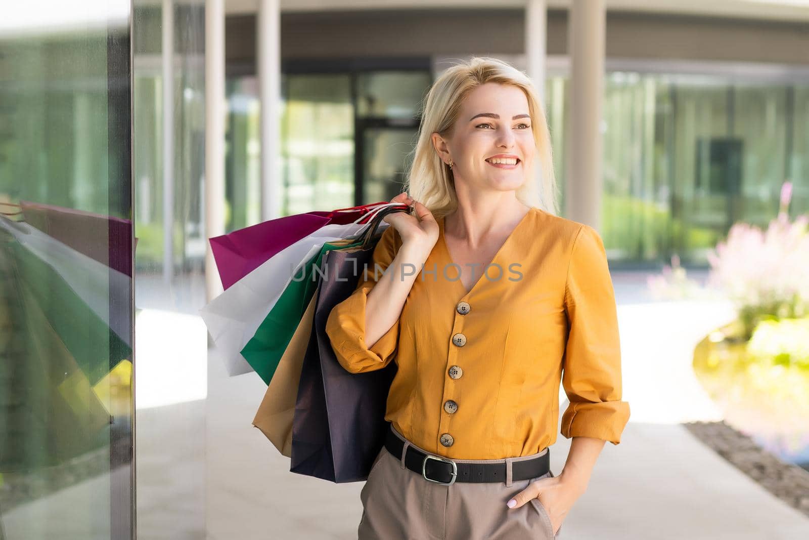 Happy woman holding shopping bags and smiling at the mall.