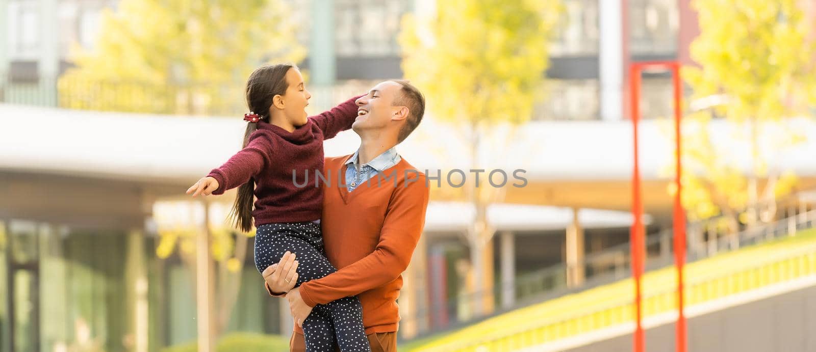 Happy father and daughter walking together in park on an autumns day.
