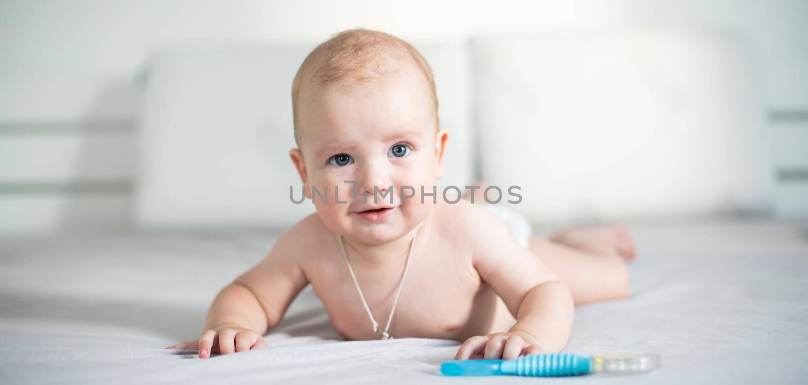 Cute smiling baby on a gray couch.