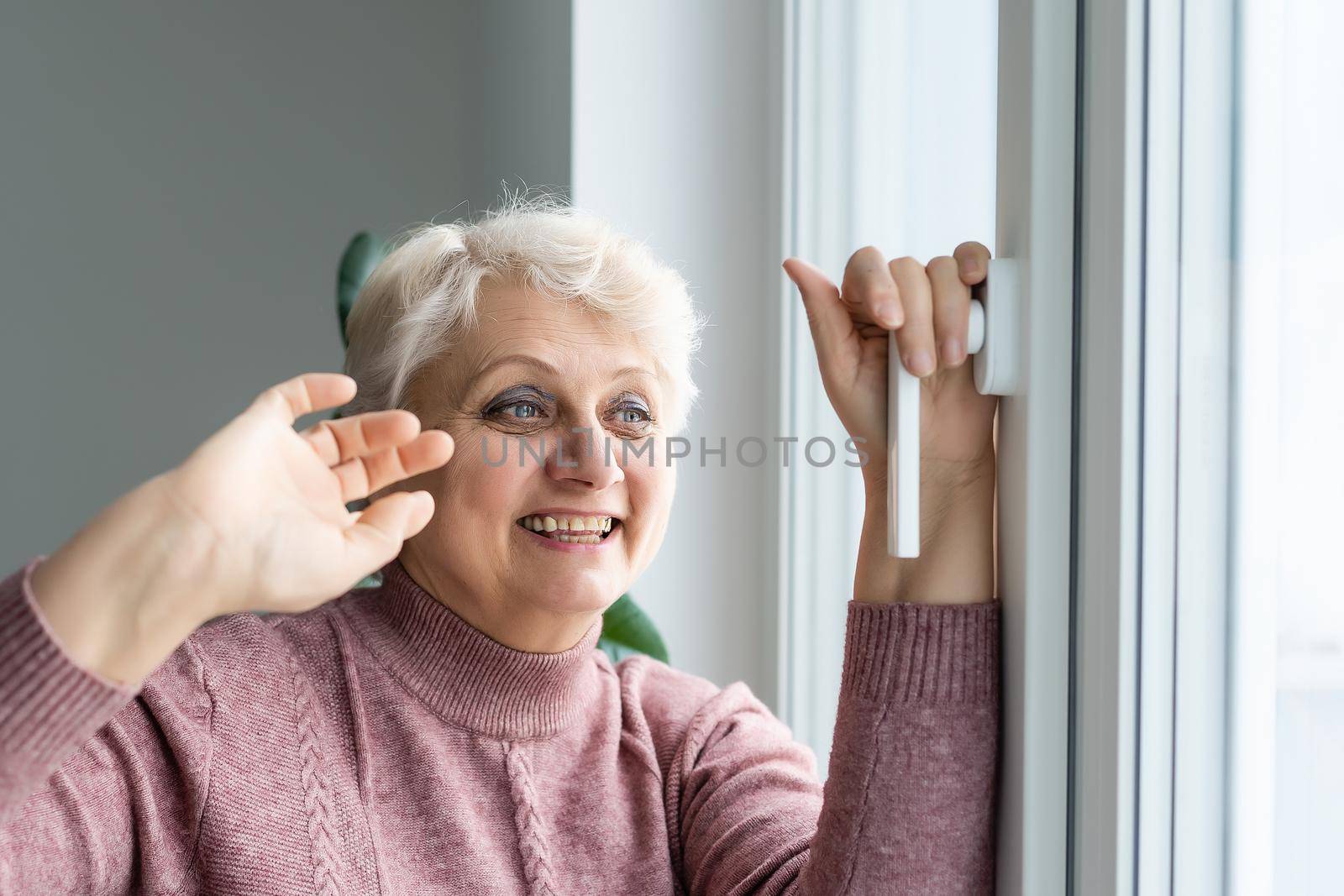 Senior woman resting at home standing near the window elderly lifestyle close-up.