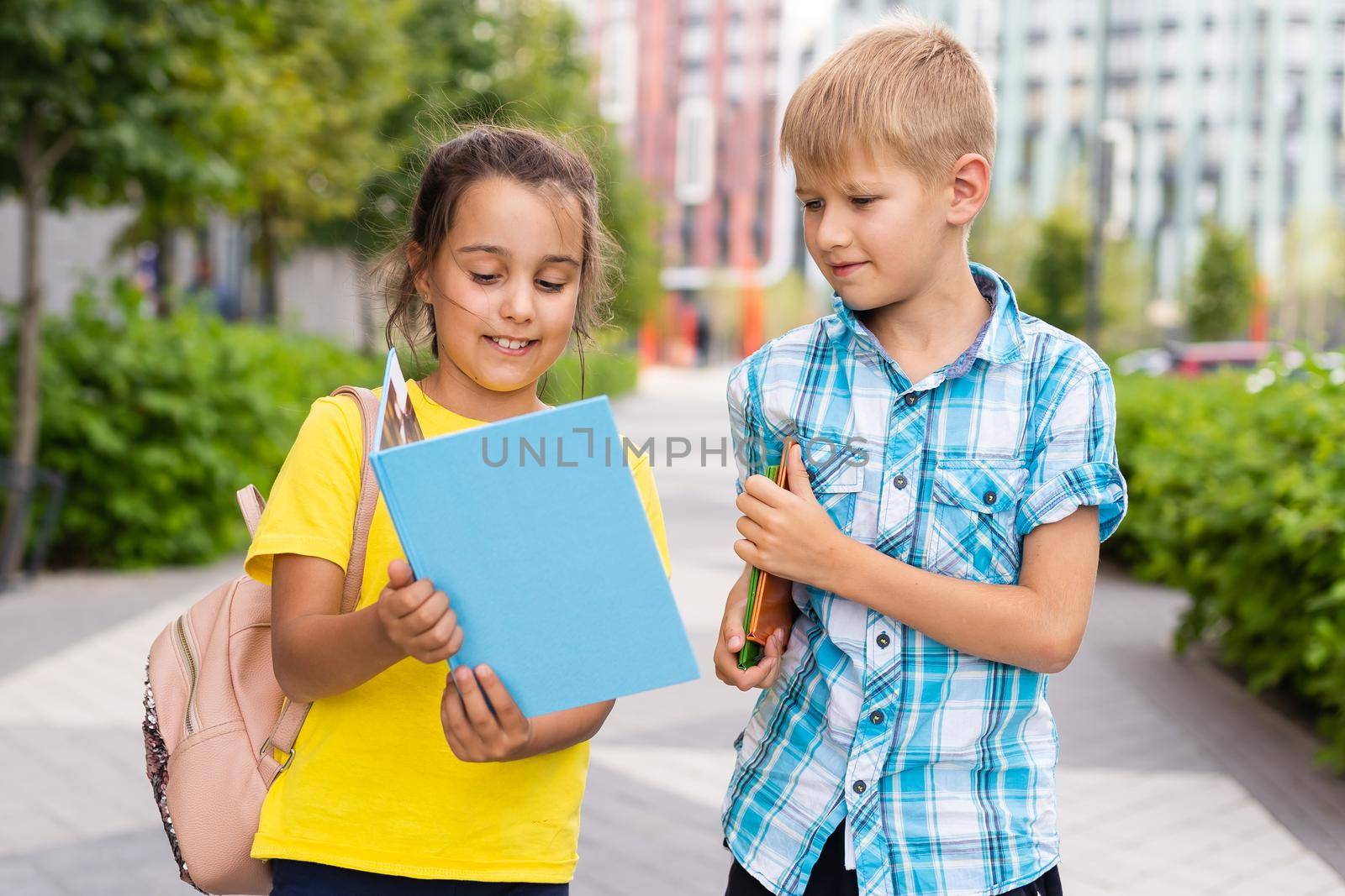 portrait of boy with girl walking to school along with backpack behind.