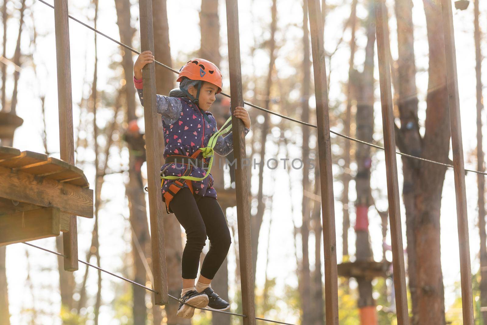 Girl climbing in adventure park is a place which can contain a wide variety of elements, such as rope climbing exercises, obstacle courses and zip-lines.