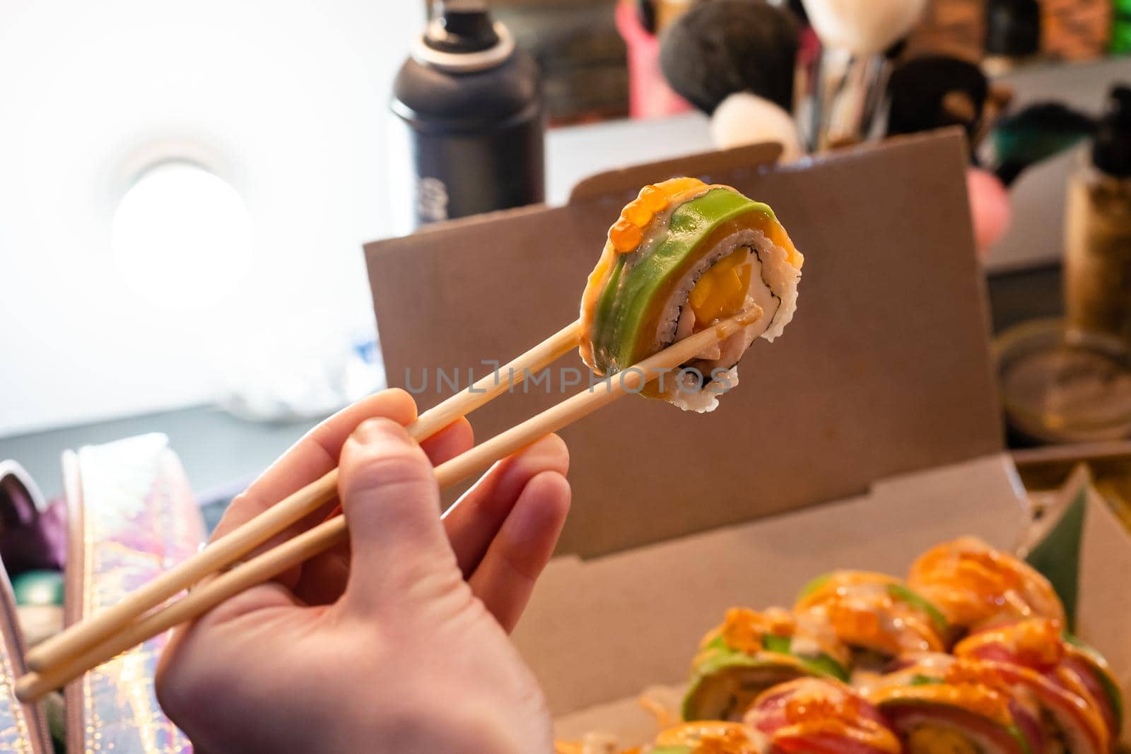 Beautiful young woman eating sushi roll at cafe. Woman eating sushi set with chopsticks on restaurant.