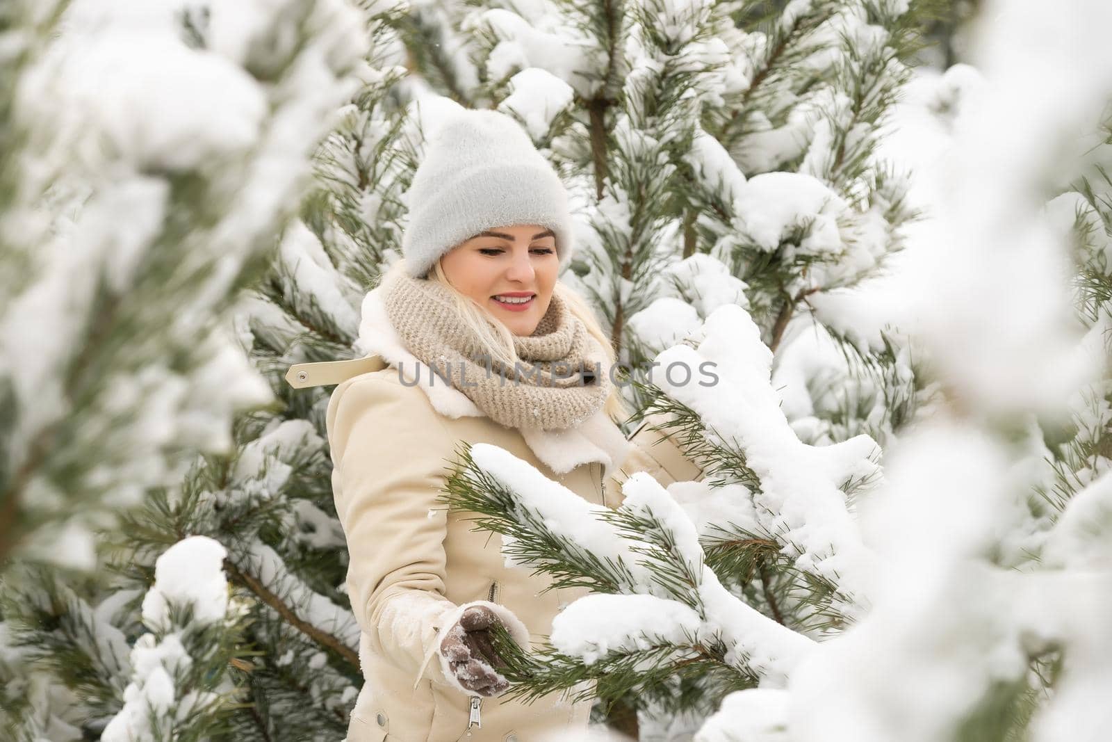 Beautiful woman standing among snowy trees in winter forest and enjoying first snow. Woman in winter woods. pines