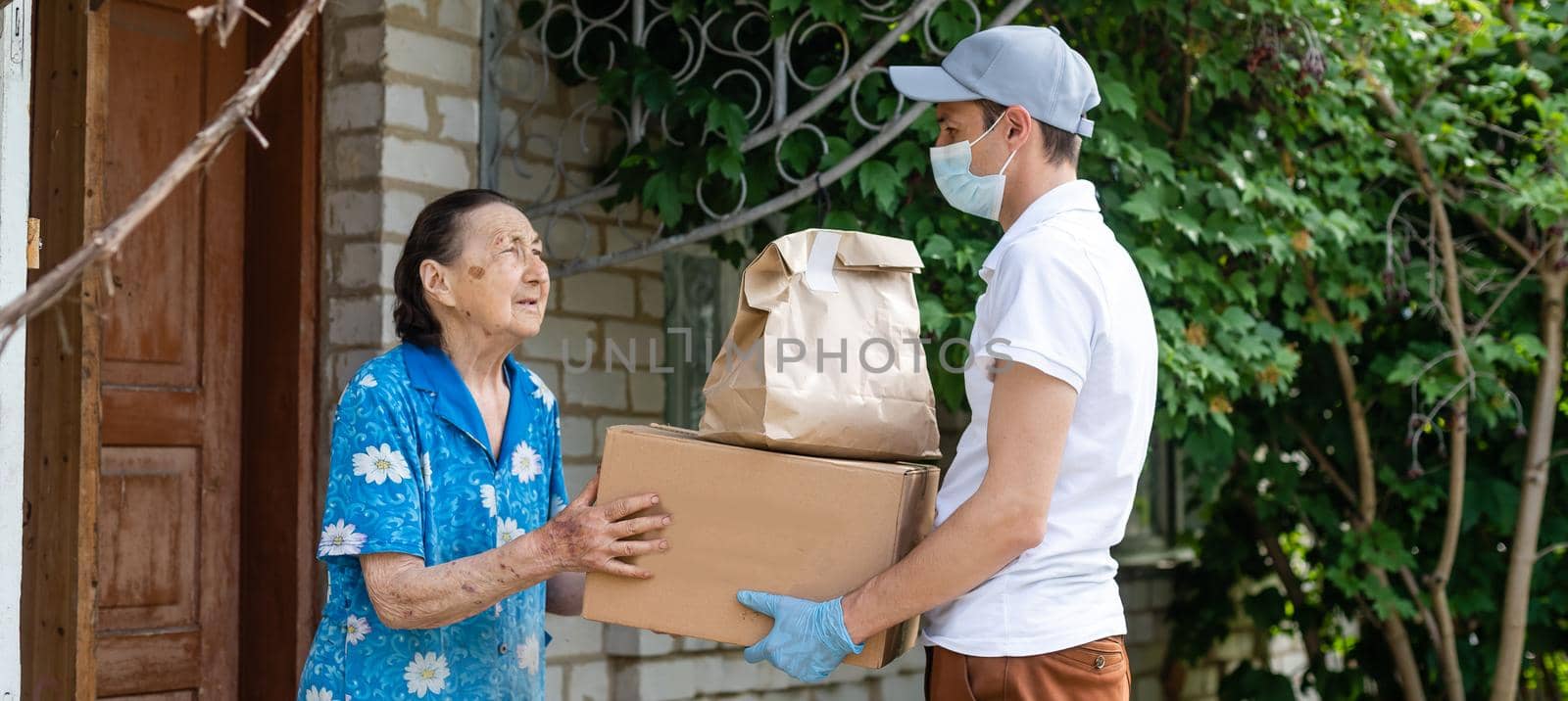 Elderly woman paying courier of food delivery company for order via terminal. Concept of epidemic.