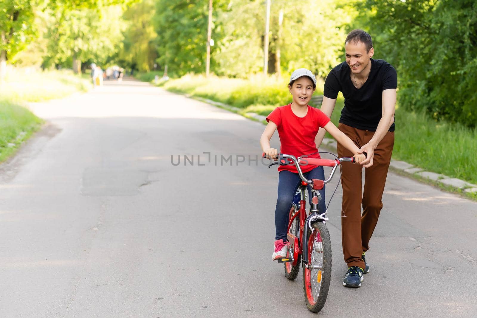 loving father teaching daughter to ride bike by Andelov13