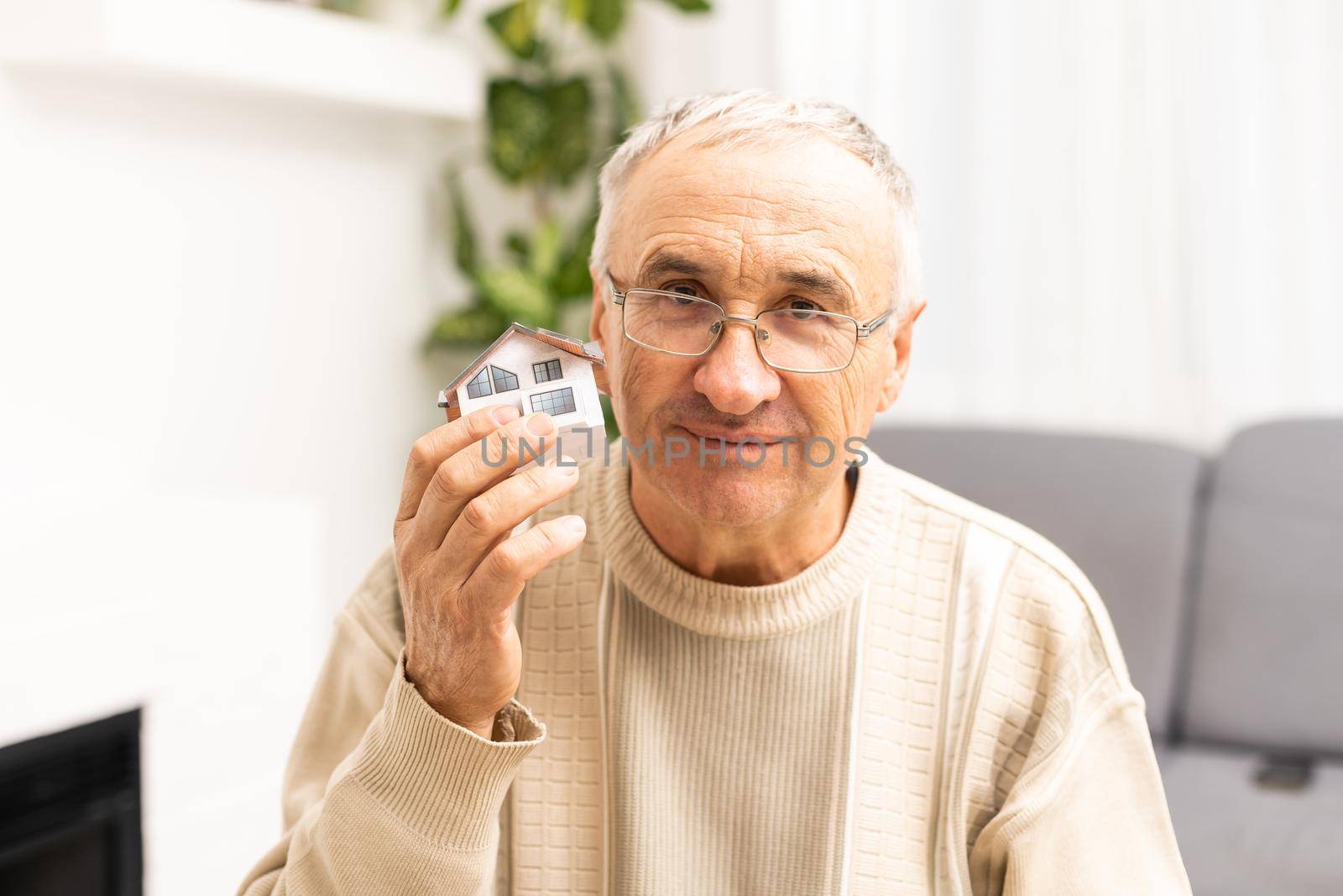 Senior elderly man with house model.