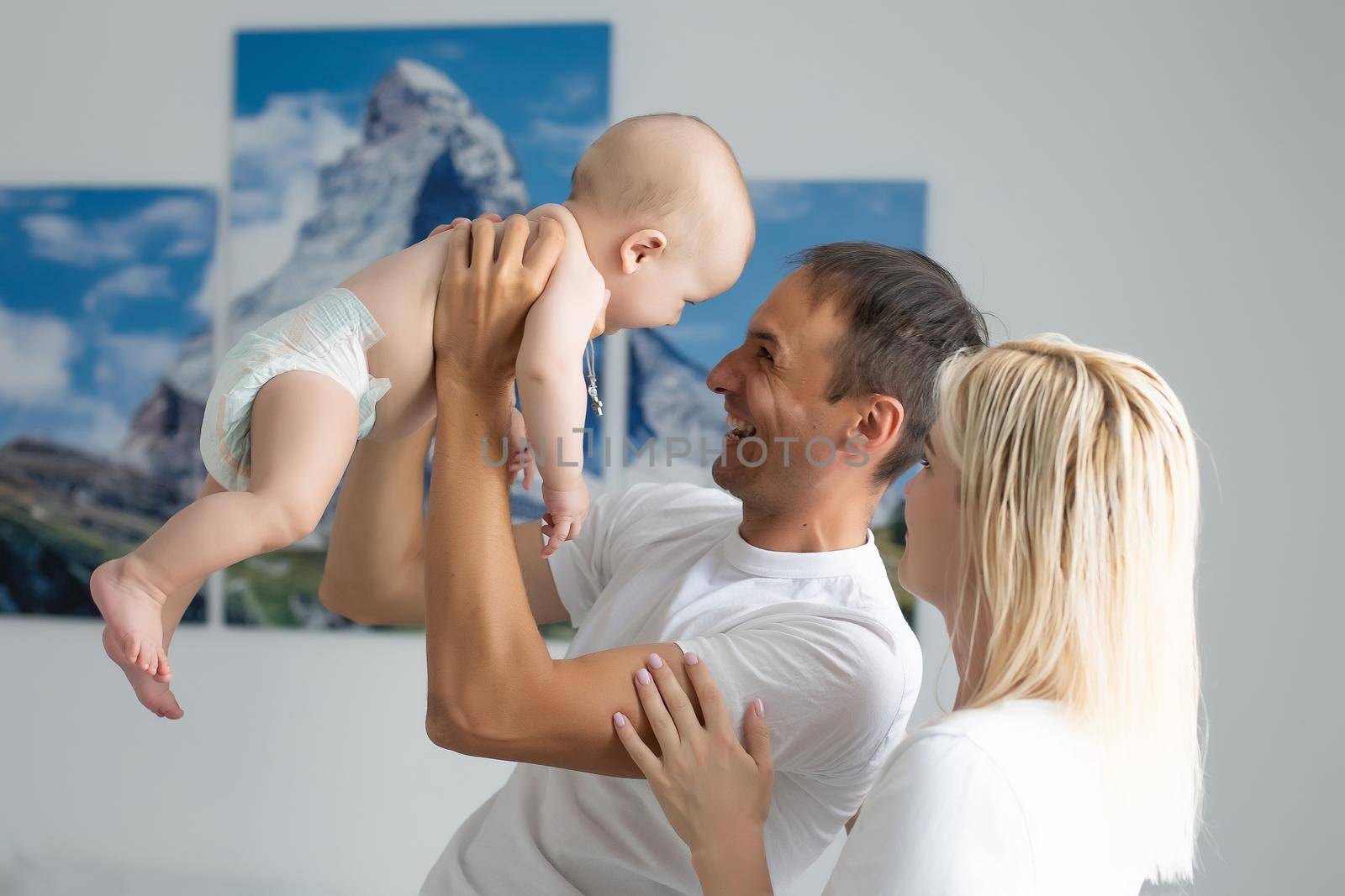 Portrait of happy young parents with baby at home.