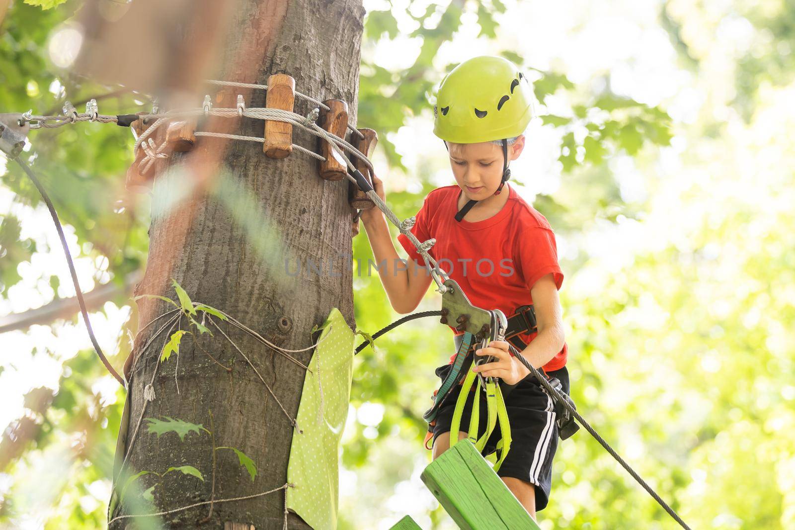 Cute school boy enjoying a sunny day in a climbing adventure activity park.