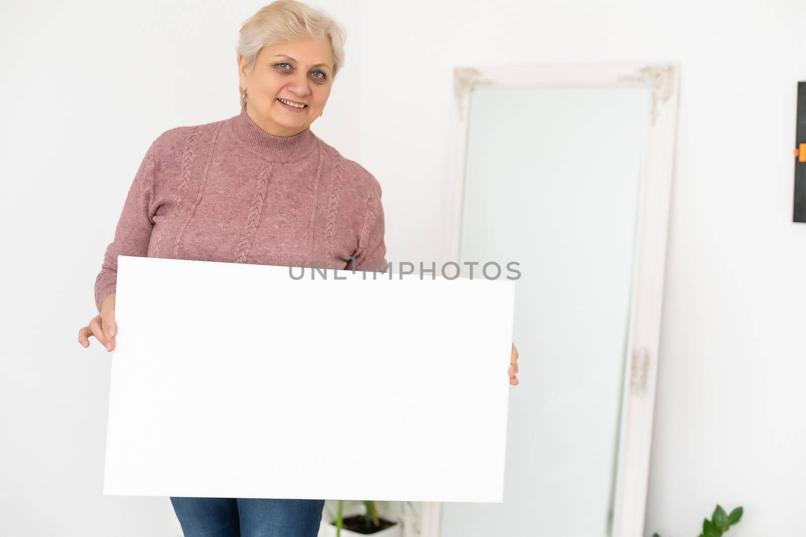elderly woman holds a photo canvas.
