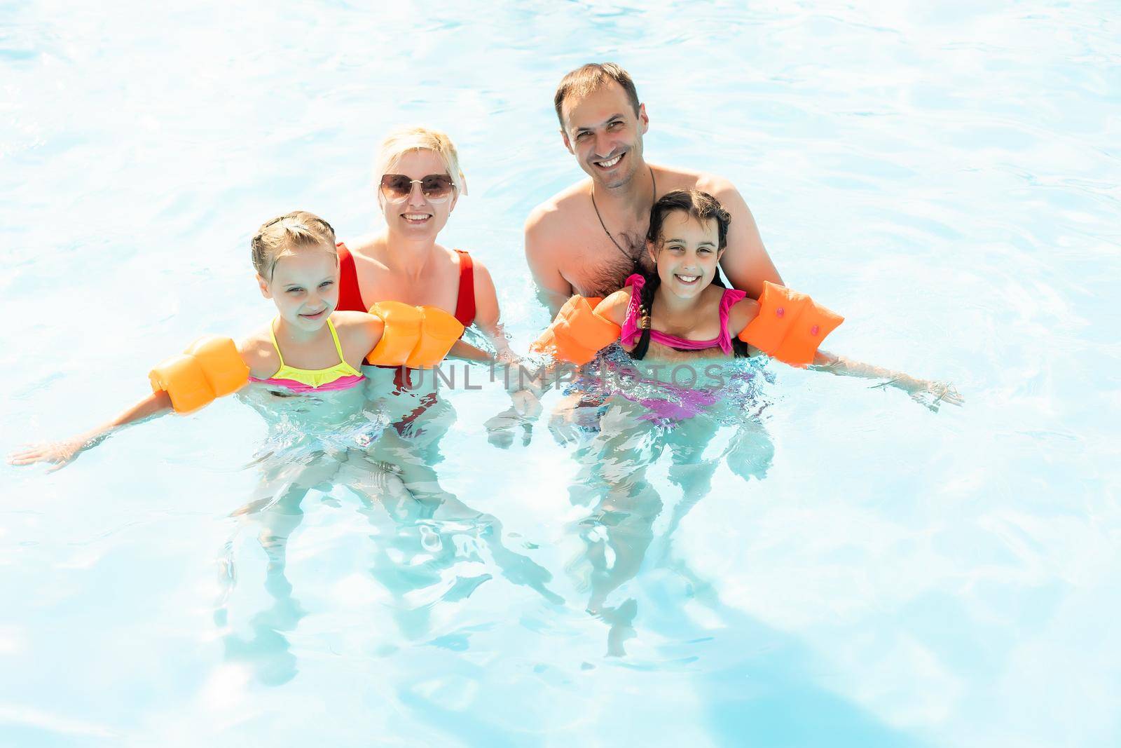 Happy family playing in swimming pool. Summer vacation concept.