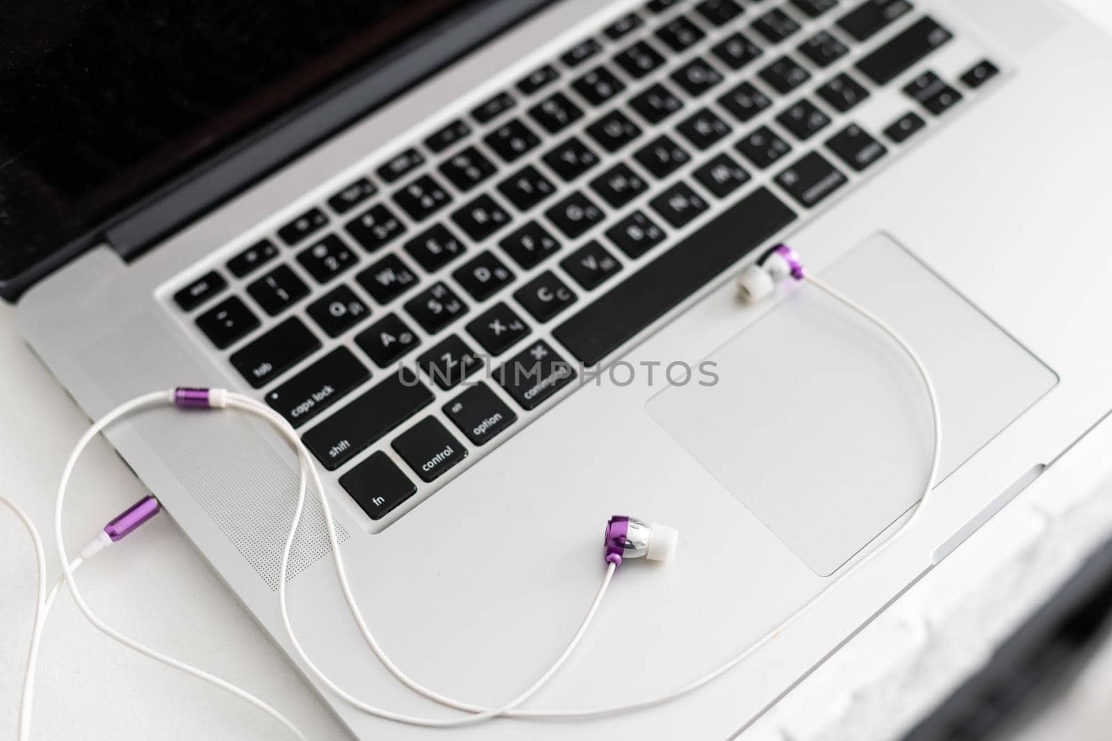 laptop keyboard with headphones and diary on table, close up