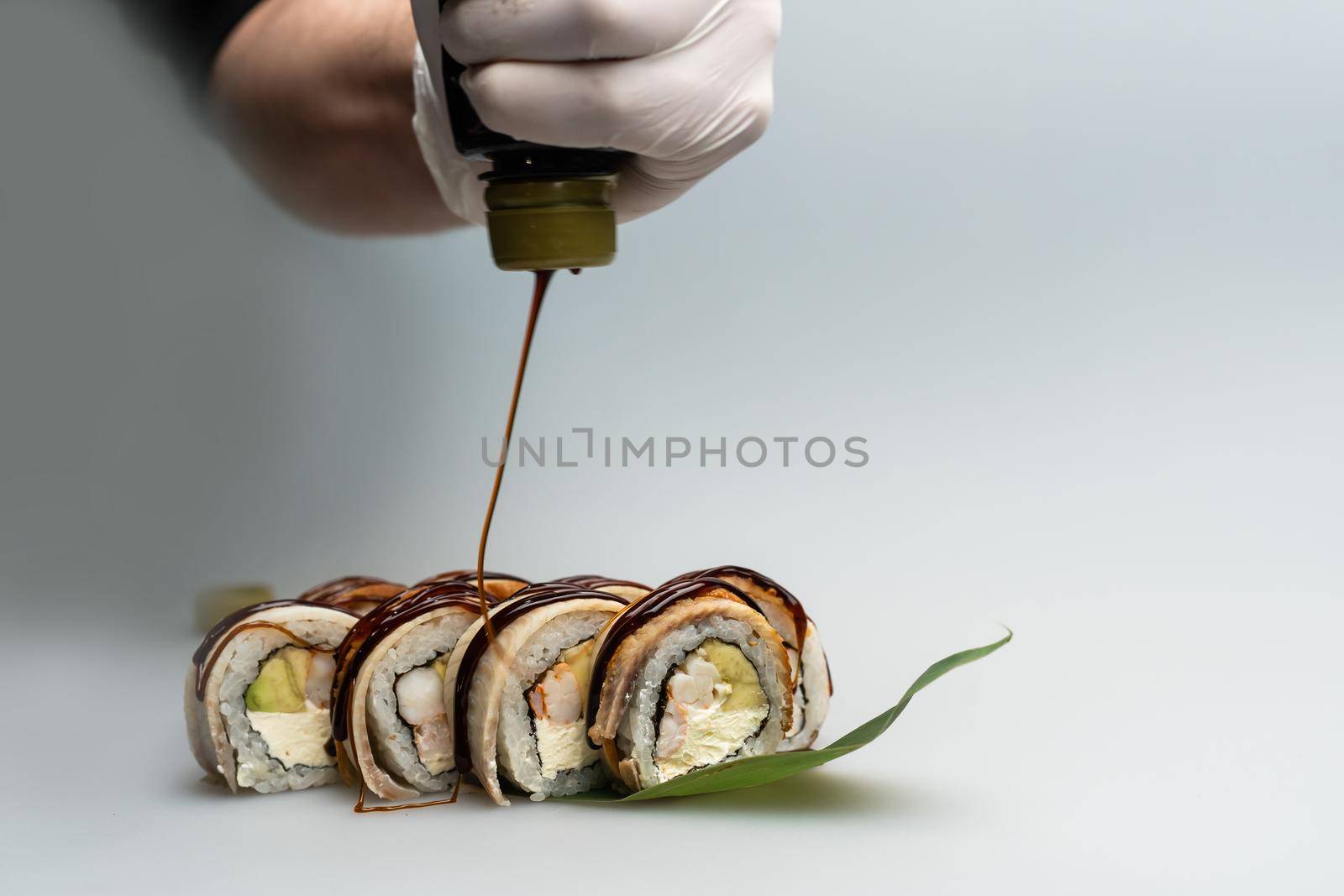 Closeup of chef hands preparing japanese food. Japanese chef making sushi at restaurant. Young chef serving traditional japanese sushi.