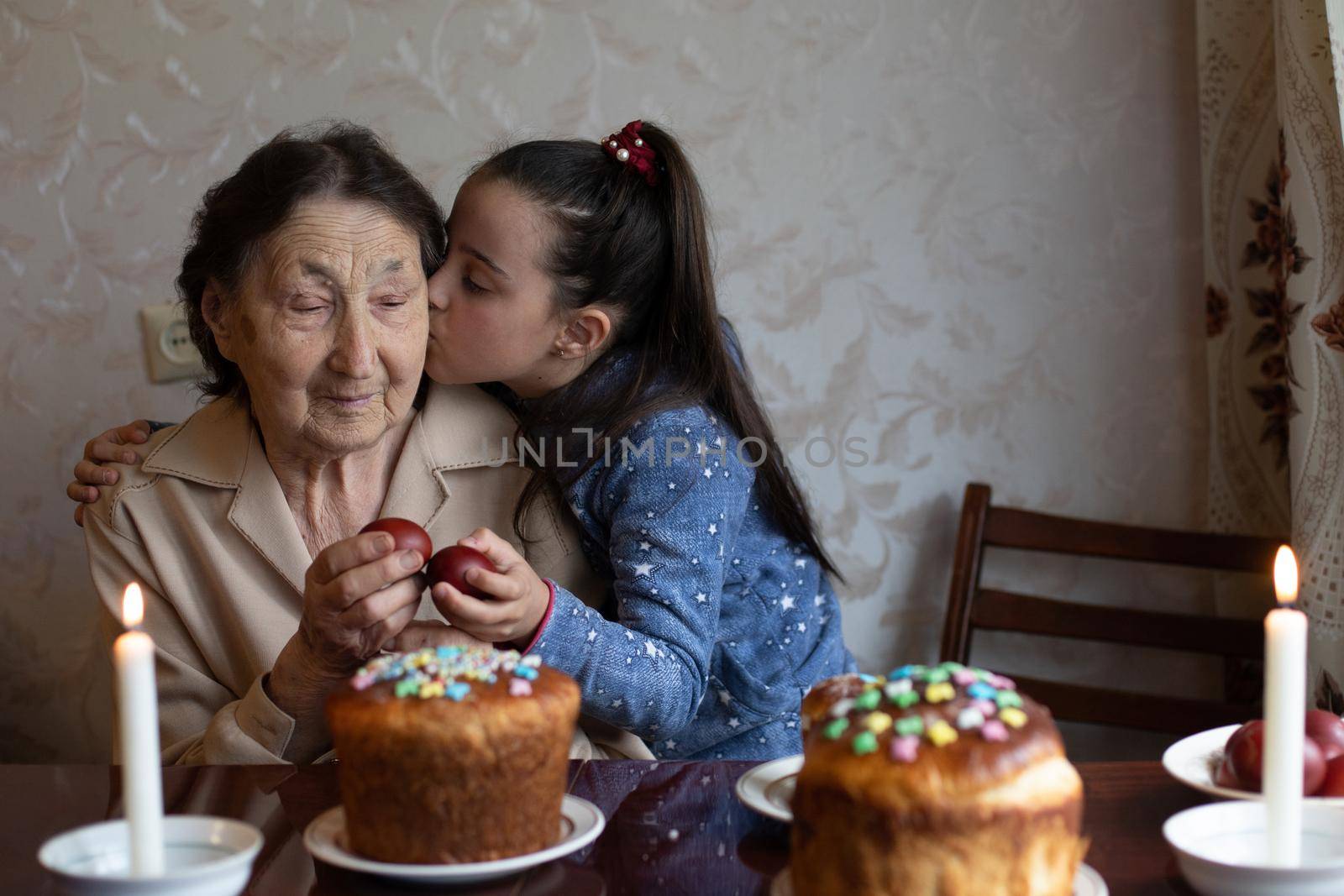 Easter concept. Grandmother with granddaughter are holding Easter eggs at home.