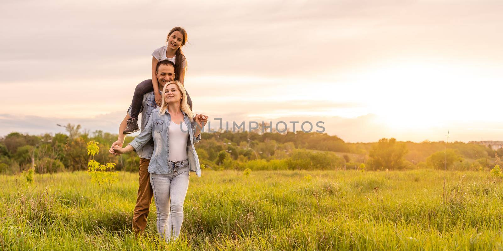 Happy family: mother father and child daughter on nature on sunset.