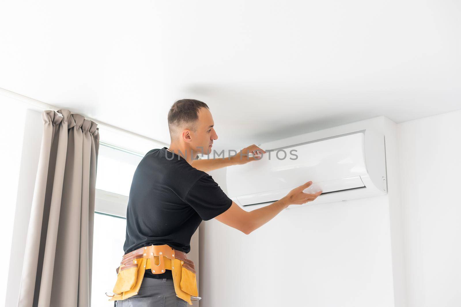 Rear View Of A Man Cleaning Air Conditioning System.