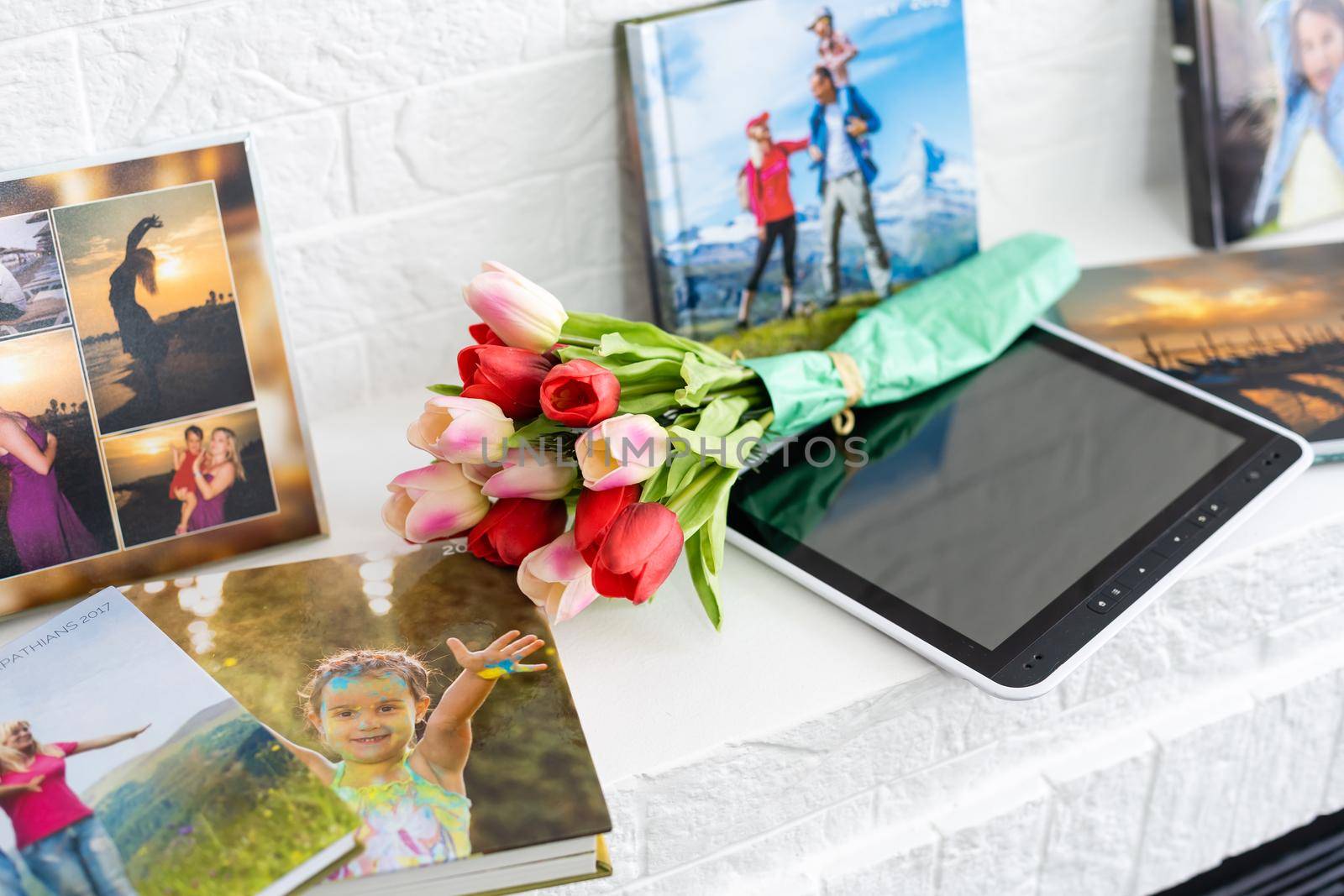 photo book and flowers tulips as a holiday gift lie on the shelf.