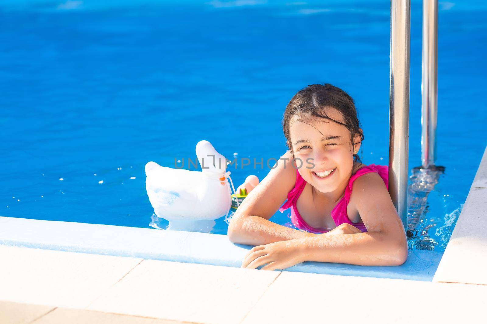 happy little girl having fun in the pool in swimming suit. by Andelov13