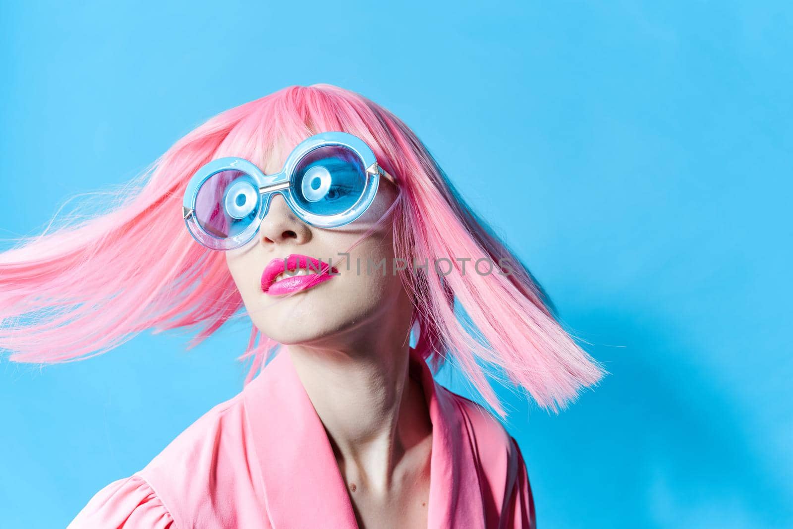 pretty woman in blue glasses wears a pink wig isolated background by SHOTPRIME