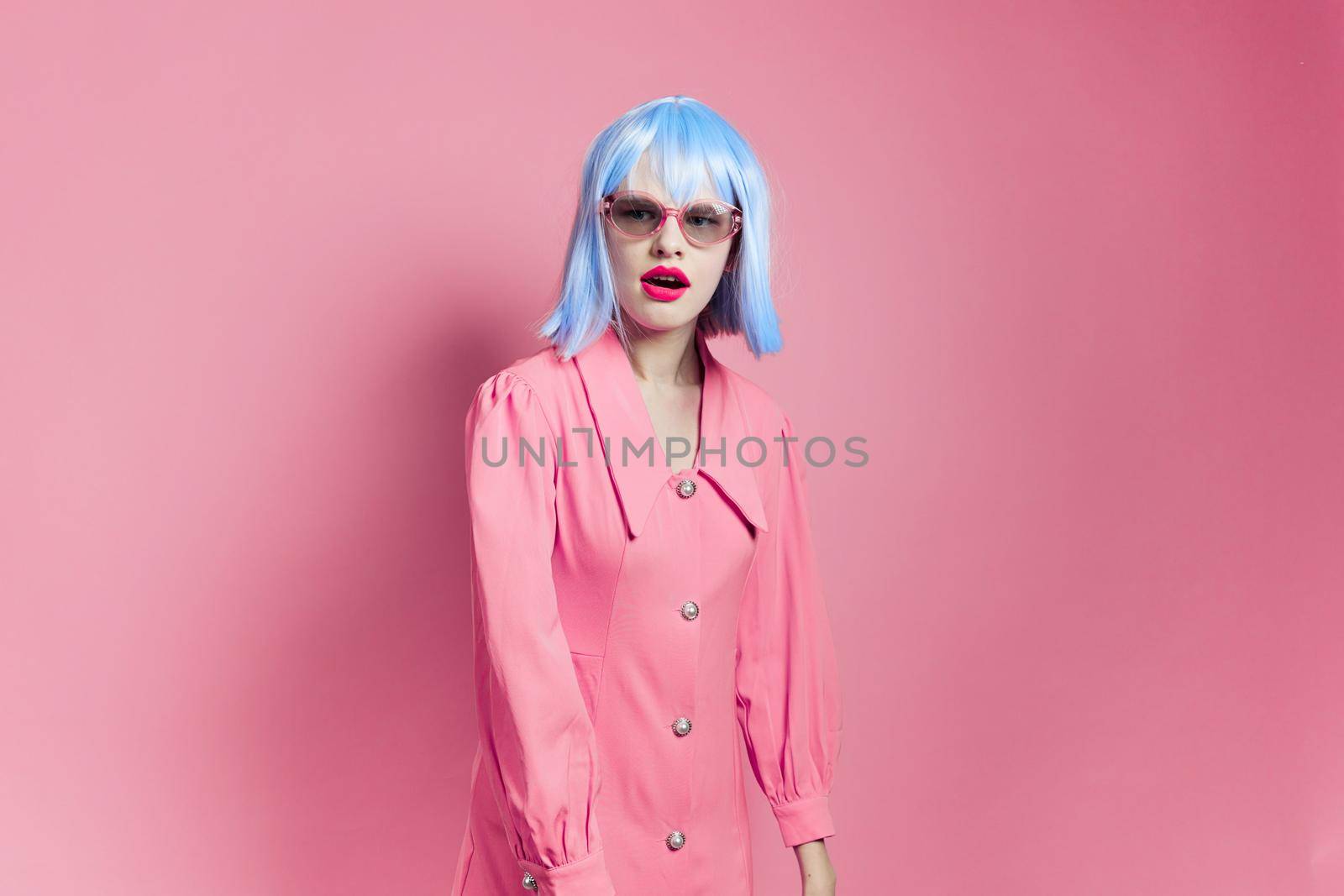 fashionable woman in sunglasses wears a blue wig makeup pink background by SHOTPRIME