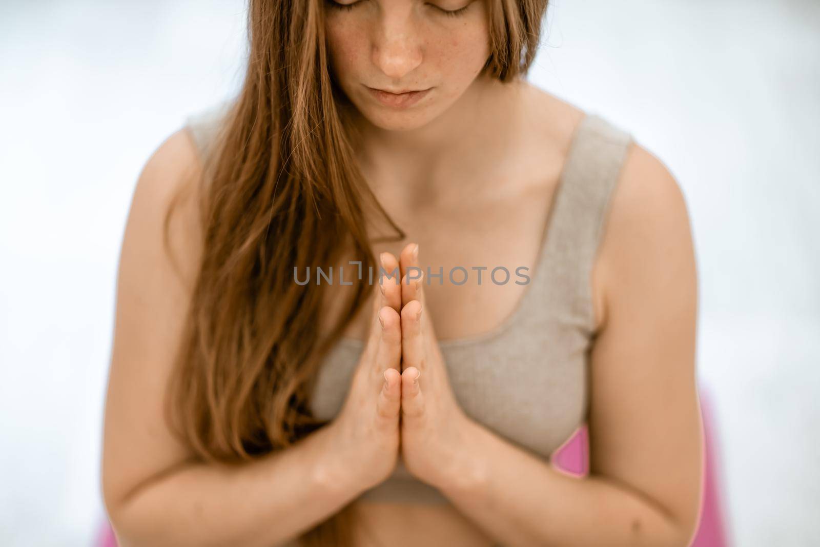 Girl does yoga. Young woman practices asanas on a beige one-ton background