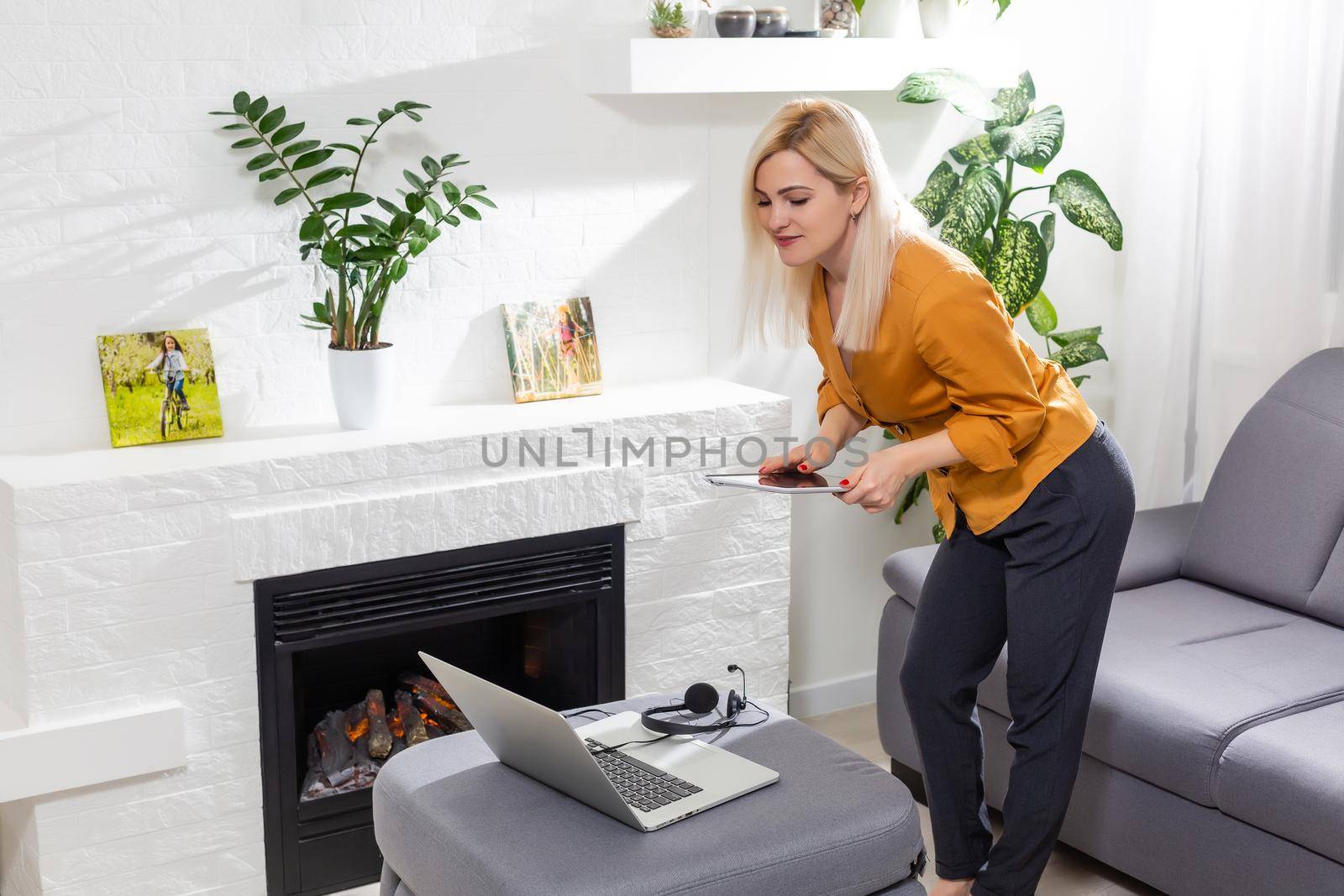 Middle-aged woman reading a message, e-book or information on her tablet computer with a look of excited anticipation at home by Andelov13
