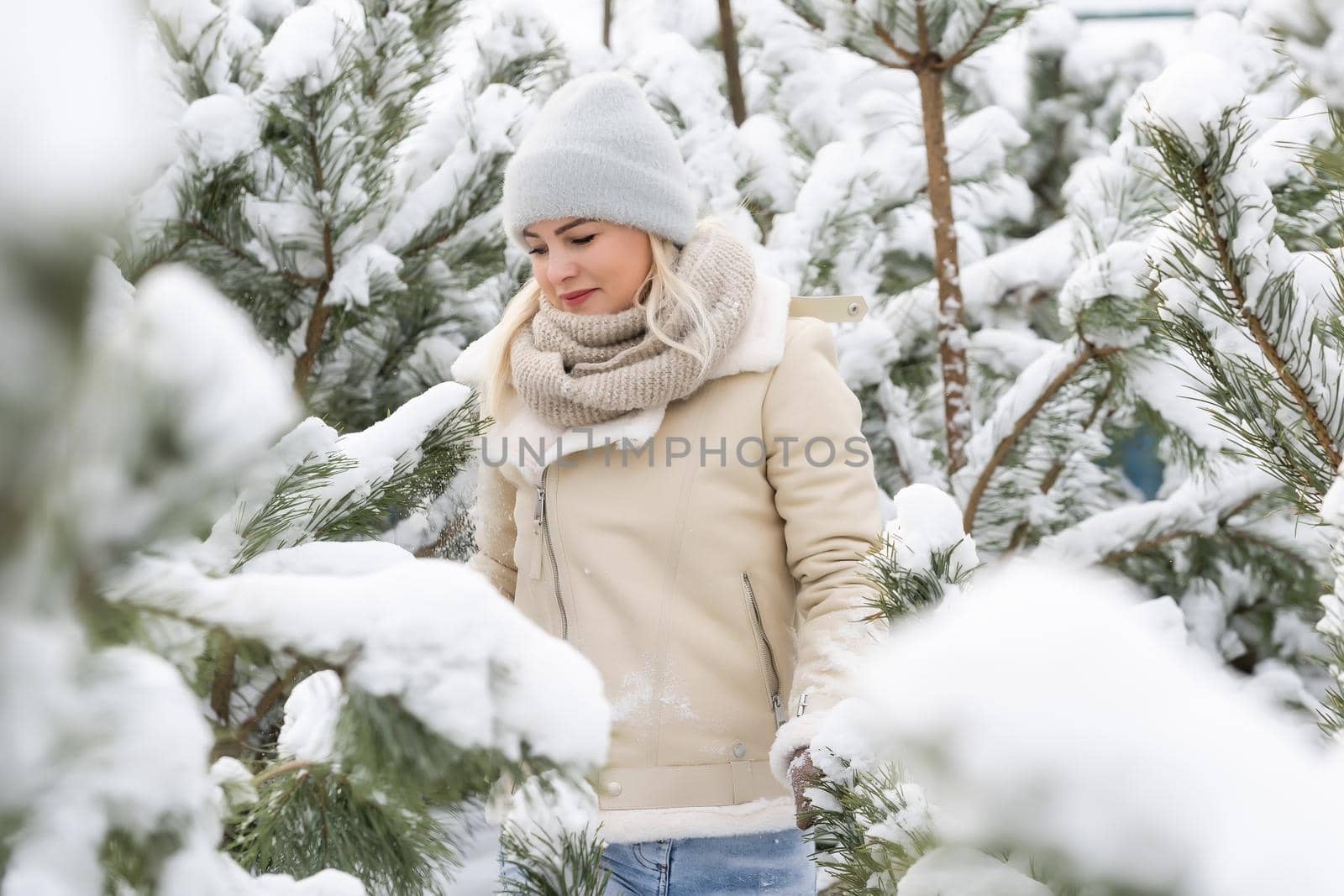 Beautiful woman standing among snowy trees in winter forest and enjoying first snow. Woman in winter woods. pines