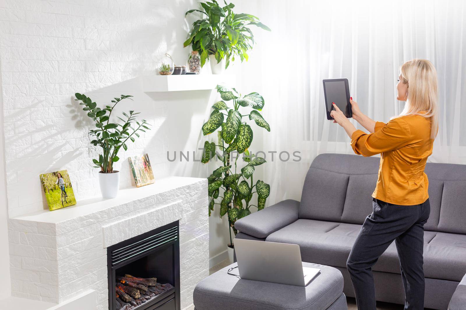 Woman using digital tablet by fireplace at home