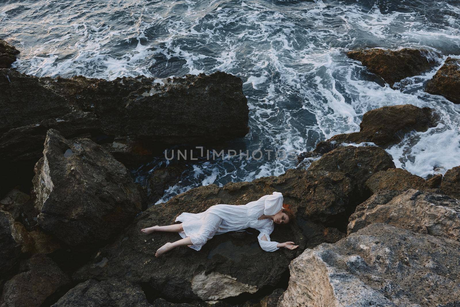 Barefoot woman in white wedding dress on sea shore wet hair view from above. High quality photo