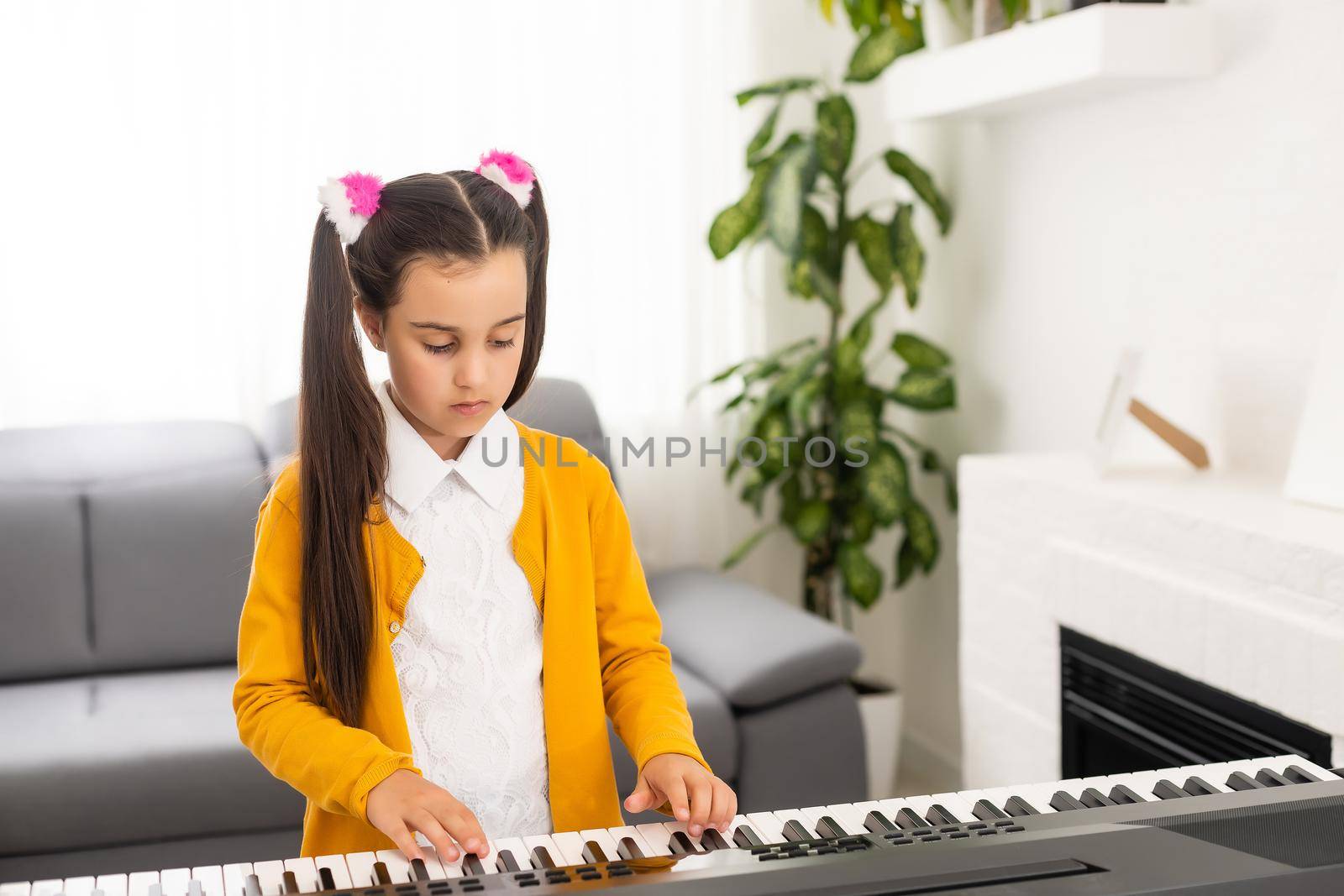 beautiful little girl playing piano in light room by Andelov13
