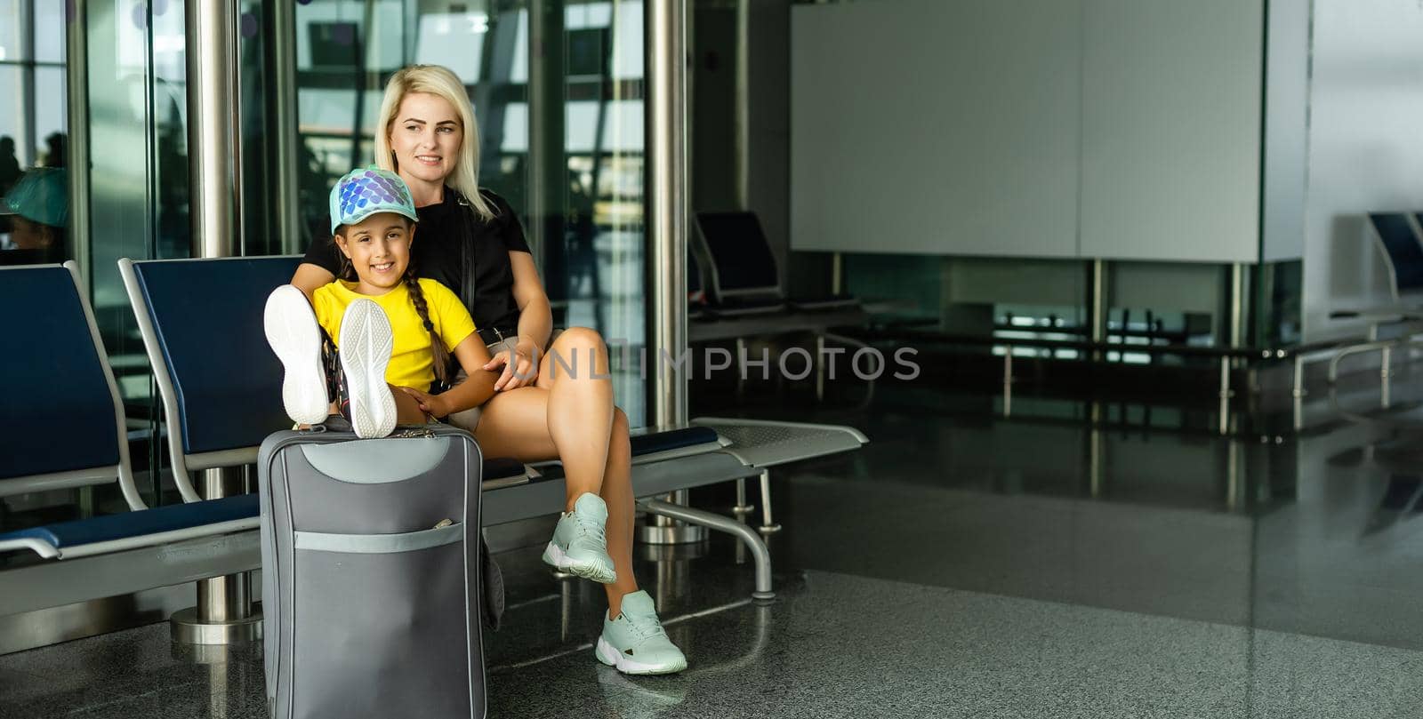 Mother with daughter in masks waiting for their flight at airport. Woman with little girl in international airport