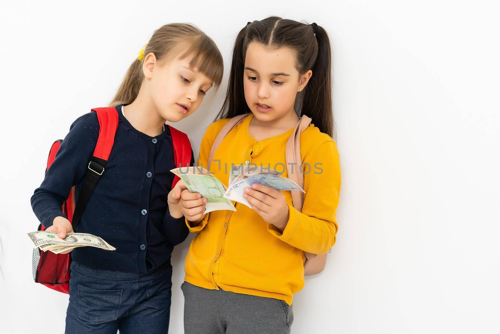 two little girls with money dollar and euro.