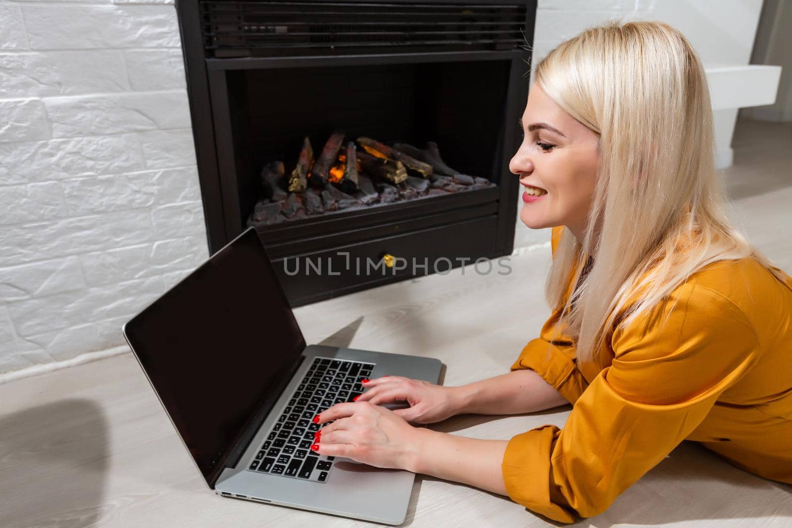 Happy casual beautiful woman working on a laptop sitting in the house.