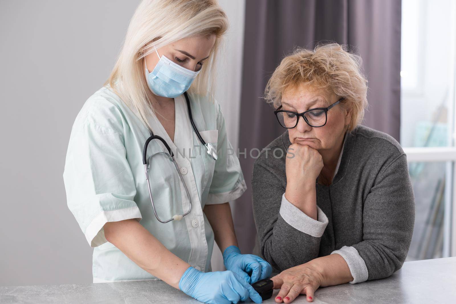 Close-up photo of a female hands. Woman doctor measures the patient's pulse and oxygen saturation to middle aged woman using a pulse oximeter, healthcare concept. by Andelov13