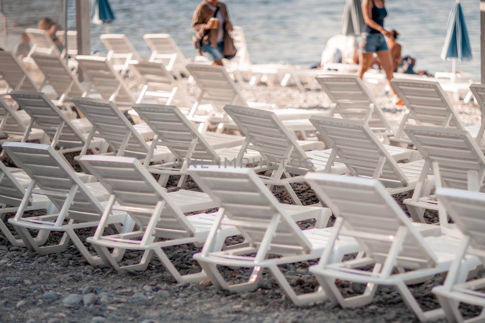 Several white sun loungers and an umbrella on a deserted beach. The perfect vacation concept