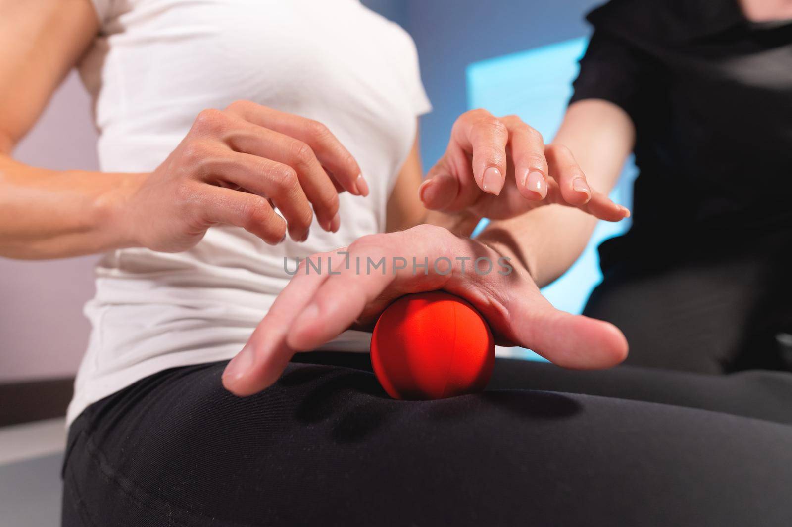 Close-up of a male massage therapist showing a client how to use and massage a ball. Myofascial thigh massage by yanik88