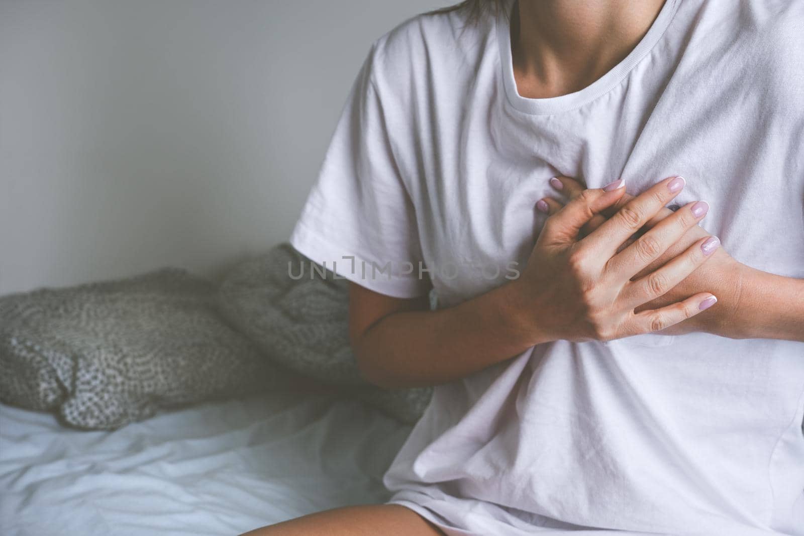 Woman holding chest because of heart disease, heart attack, heart pain or chest pain by DariaKulkova