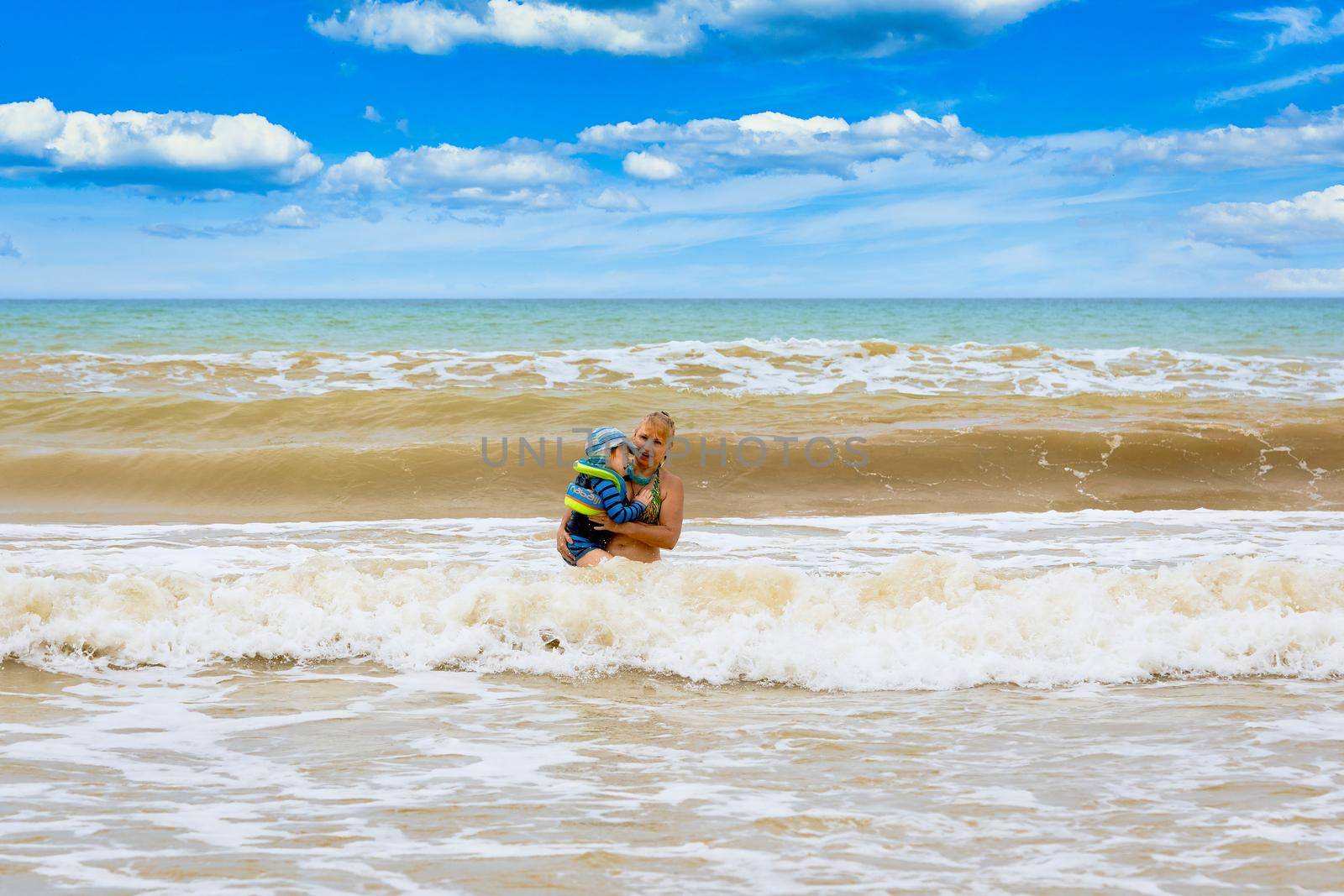 A woman carries in her arms a child from a stormy sea. Rescue a child into a storm