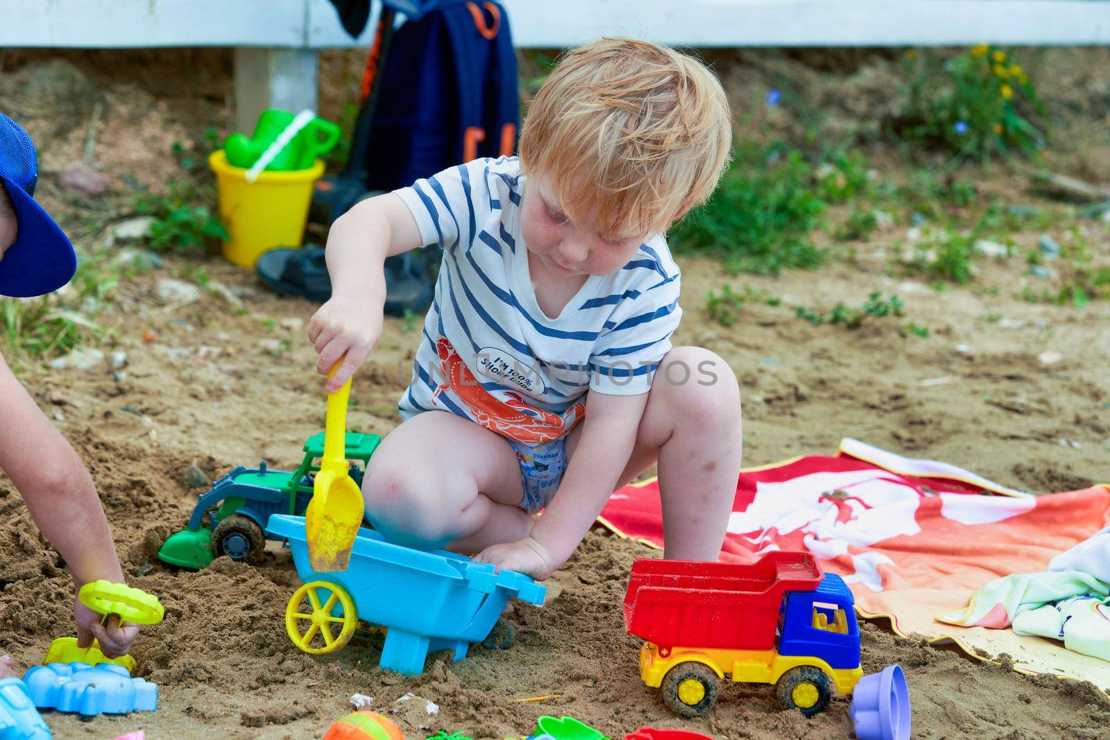 Little boy plays in the sand with plastic toys. Child playing in the sandbox