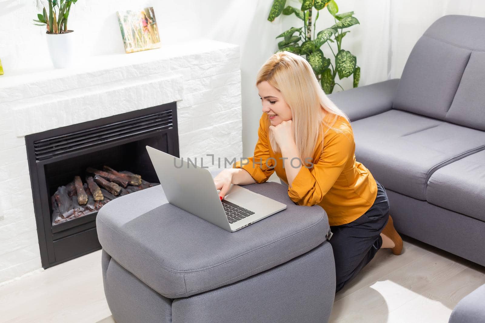 Young woman doing research work for her business. Smiling woman sitting, relaxing while browsing online shopping website. Happy girl browsing through the internet during free time at home. by Andelov13