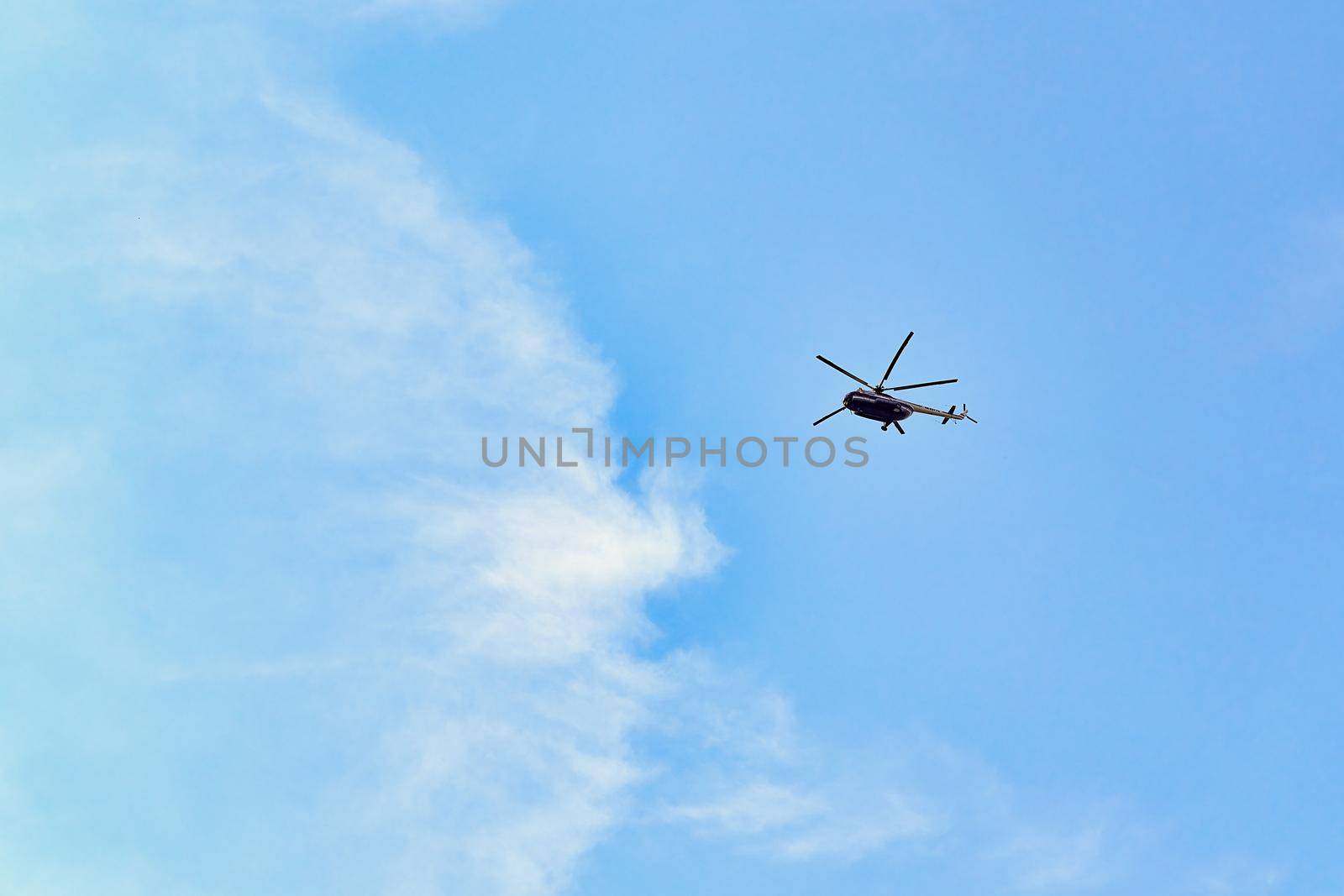 Flying helicopter against the background of a blue sky with spruce clouds. Blank for designers