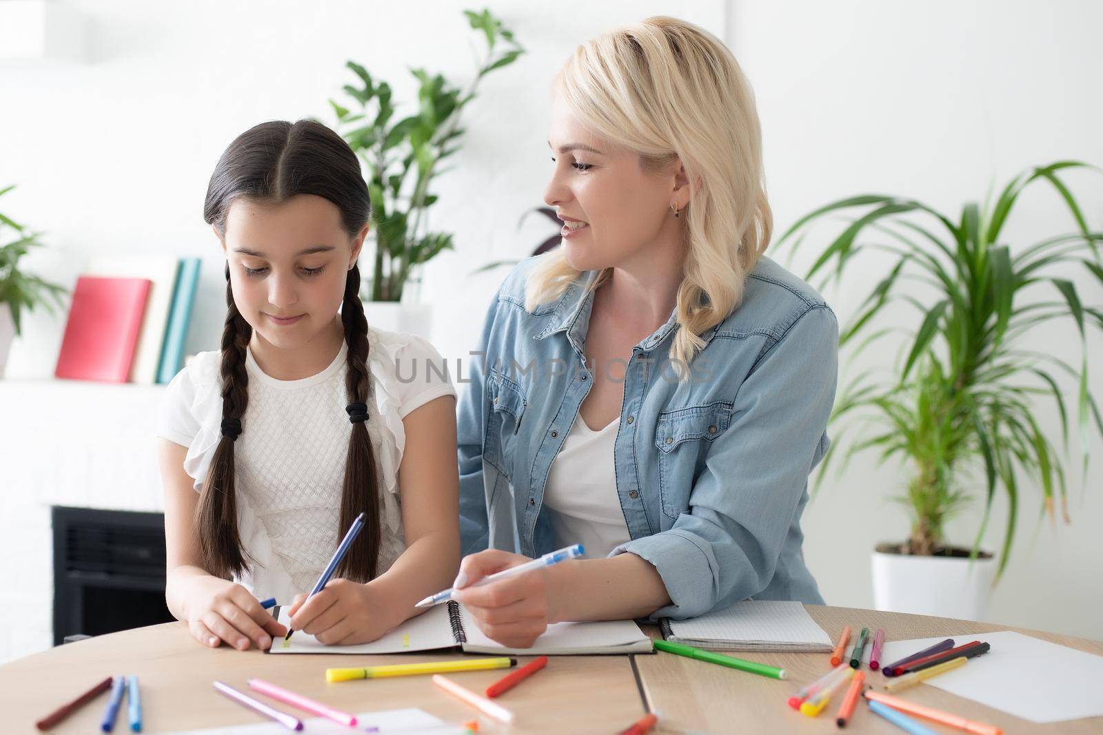 Little girl educating at home with her mother symbols drawn over her head by Andelov13