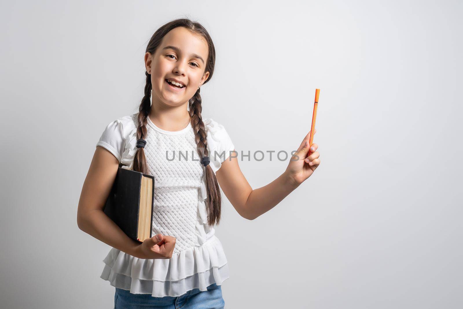 Lovely little girl standing and holding book over white background.
