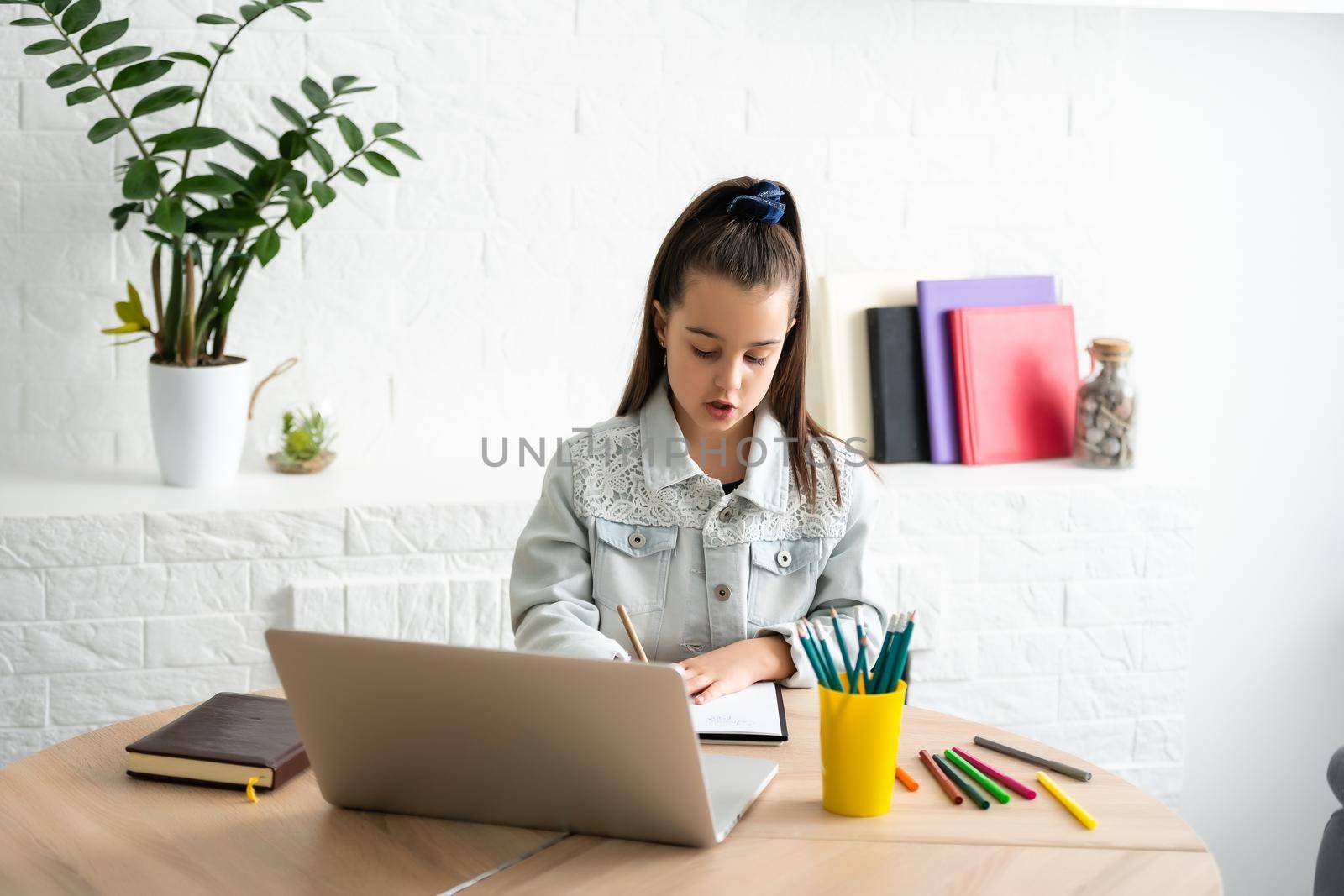 Student little school girl homework on laptop computer silver background