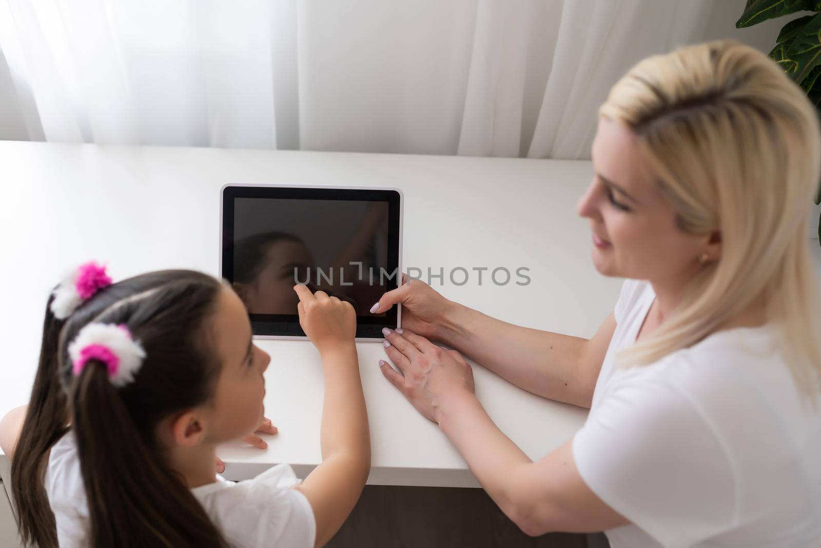 Online education of children. Mother and daughter of preschool watching a video lesson call chat at home. by Andelov13