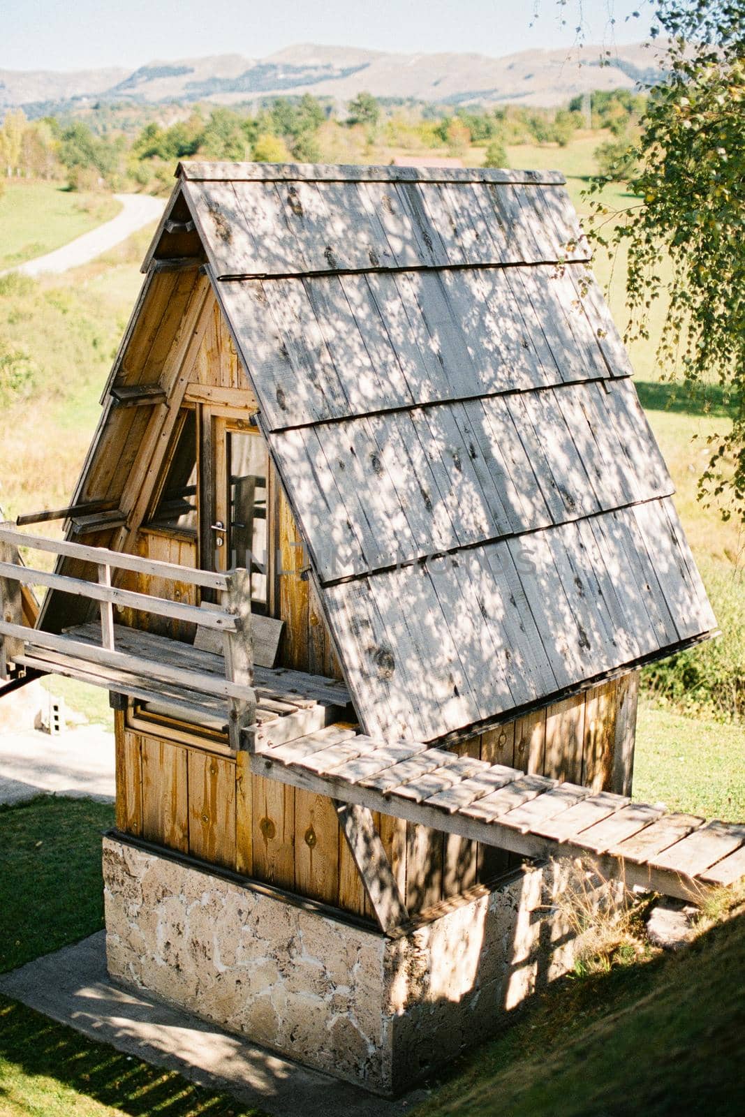 Triangular house with a balcony and a wooden bridge to the hill. High quality photo