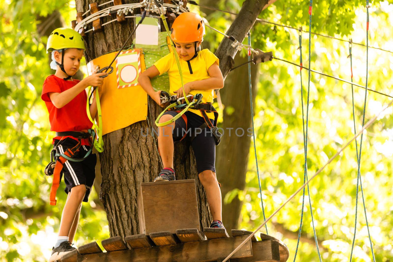 Happy child climbing in the trees. Rope park. Climber child. Early childhood development. Roping park. Balance beam and rope bridges. Rope park - climbing center.