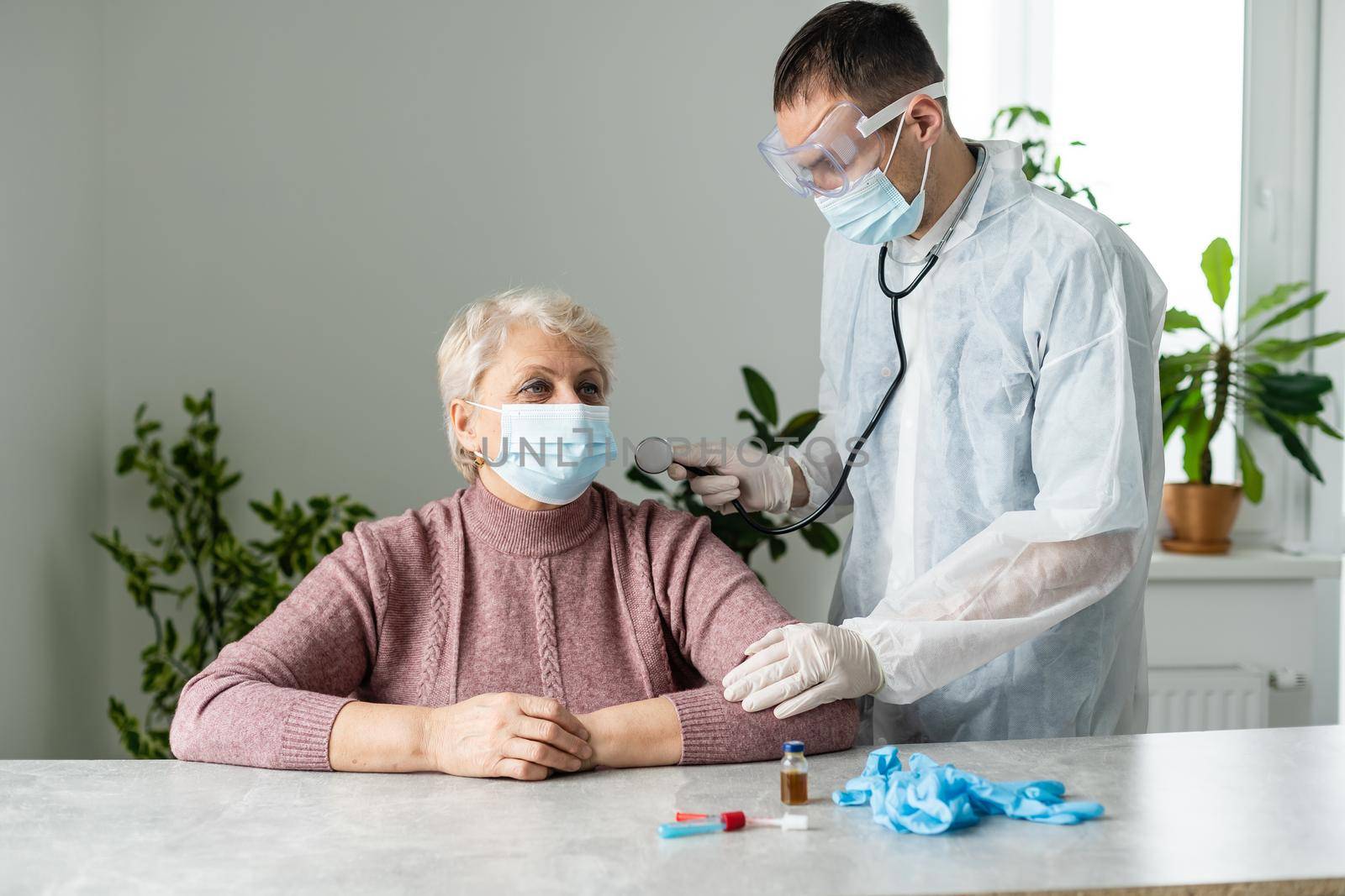 In modern private clinic doctor is listening heart of senior patient sitting on hospital bed. Healthcare medical medicine consultation, using stethoscope giving professional treatment to sick ill.