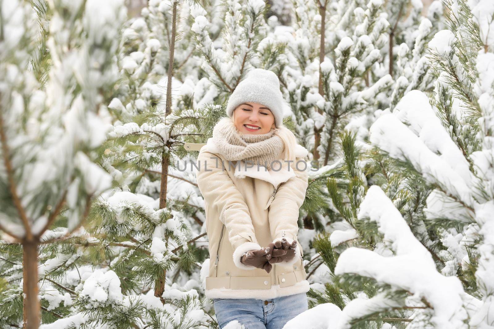 Beautiful woman standing among snowy trees in winter forest and enjoying first snow. Woman in winter woods. by Andelov13